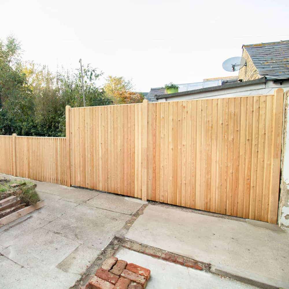 a premier larch fence of two heights in a garden.