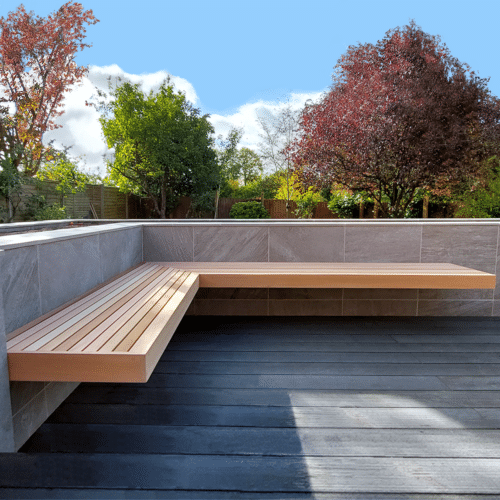 floating garden bench fixed to a wall in a contemporary garden with a beautiful tree in the background