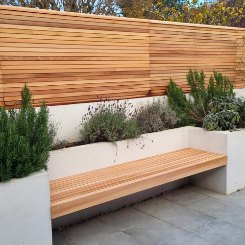 A Cedar floating bench beside a matching Cedar fence panel, also by Contemporary Fencing.