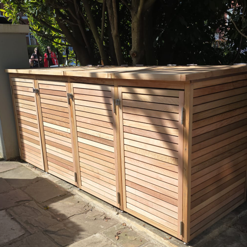 A Cedar wheelie bin store / storage unit sitting in the shade of a gorgeous garden. 240L standard bin storage.