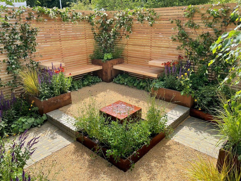 A bespoke garden seating area, hidden by slatted fencing and filled to the brim with gorgeous plants.