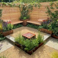 A bespoke garden seating area, hidden by slatted fencing and filled to the brim with gorgeous plants.