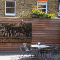A contemporary fence in a courtyard with outdoor artwork.