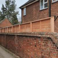 A view of the rear of a top of wall fence showing the posts and backs of the fence panels.